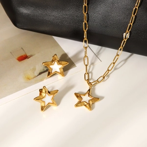 Detailed view of gold stainless steel star necklace and stud earrings set on a table