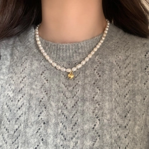 Close-up of natural freshwater pearl necklace with a gold heart pendant on a model