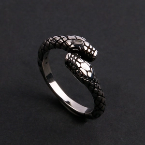 Detailed view of silver dual snake head ring with intricate scale textures on dark background