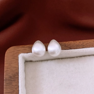Macro detail of 18k gold plated brushed teardrop earrings with matte pearl finish