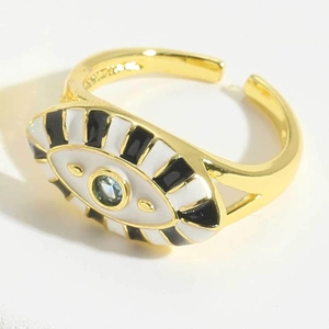 Detail of gold evil eye ring with black-white enamel and blue stone on white background