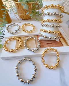 Detailed view of gold and silver beaded bracelets with alternating sizes on display