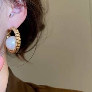 Detail of vintage gold plated pearl hoop earrings with elegant textured winding craft