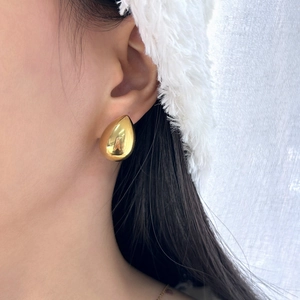 Close-up of elegant gold teardrop earrings worn by model with a soft luxury aesthetic