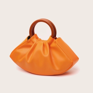 Detail of orange pleated cloud bag featuring retro round wooden handles and premium leather