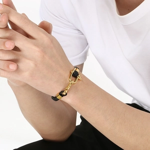 Close-up of men's black woven bracelet with golden U-shaped horseshoe buckle
