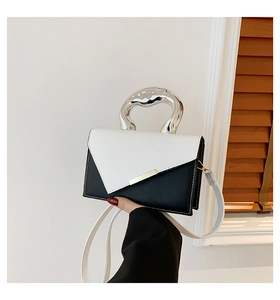Detail of woman holding a black and white leather crossbody bag with silver metal handle