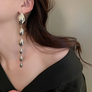 Close-up of long tiered silver teardrop dangle earrings on model for luxury style