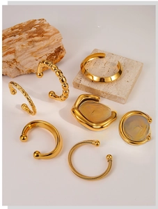 Detailed view of assorted minimalist gold open bangles with diverse textured finishes