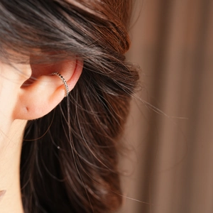 Detailed close-up of a silver beaded ear cuff clip on model's ear without piercing