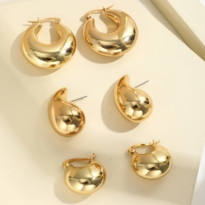 Detailansicht der glänzend goldenen geometrischen Tropfen- und Creolen-Ohrringe
