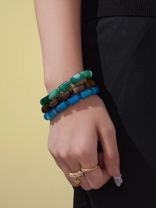 Detail von böhmischen Naturstein-Armbändern und einem goldenen Wellenring mit Diamanten