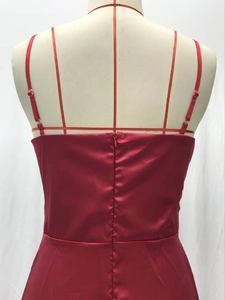 Détail d'une robe de soirée en satin rouge avec fines bretelles et fermeture éclair invisible