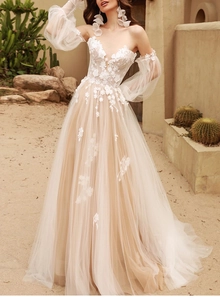Detail of 3D floral lace appliques and champagne tulle skirt on a bohemian bridal gown