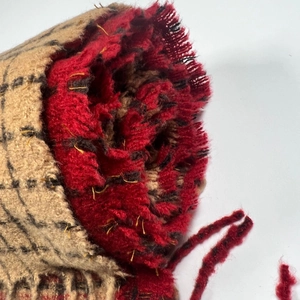 Close-up of soft red and black plaid scarf texture with elegant tassel fringe detail