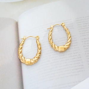 Detailed view of gold twisted oval hoop earrings featuring a stylish spiral texture design