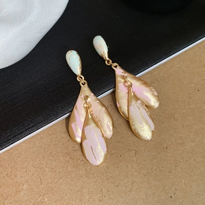 Detail of elegant two-tone leaf-shaped gold drop earrings with pink and white enamel finish