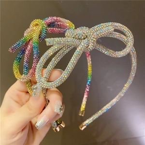 Detailed view of colorful rainbow and silver rhinestone bow headbands on hand