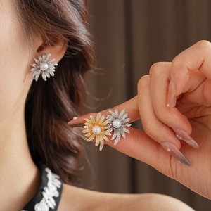 Macro shot of gold floral earrings with central pearl and shimmering pave rhinestones