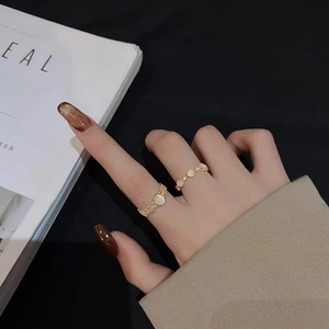 Detailed view of gold open rings with oval stone and woven texture on model's fingers