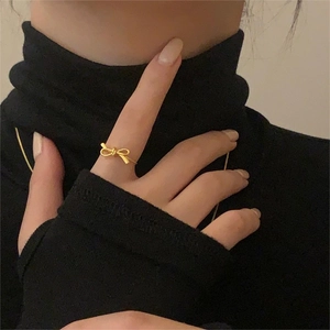 Elegant gold bow ring in S925 sterling silver worn on hand against a black background