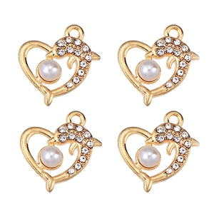 Macro detail of four gold heart pendants with crystal dolphins and pearls on white backdrop