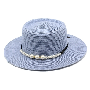 Dettaglio del cappello di paglia blu con nastro nero ed eleganti decorazioni di perle