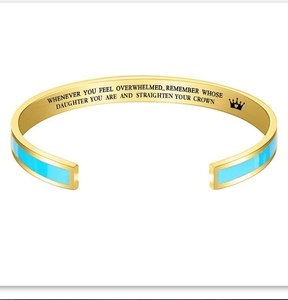 Detail of engraved inspirational message and crown on gold and blue enamel cuff bracelet