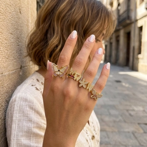 Close-up of 18K gold-plated butterfly rings with micro-pave zircons worn on hand