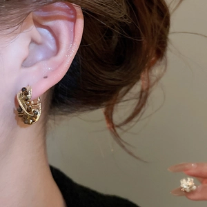 Close-up of vintage golden tiger eye bead earrings on model with warm lighting