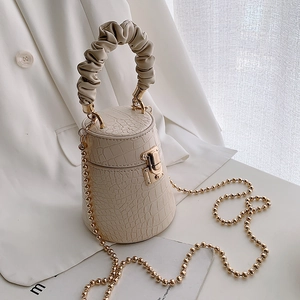 Beige crocodile pattern cylinder bucket bag with ruched handle and gold chain strap