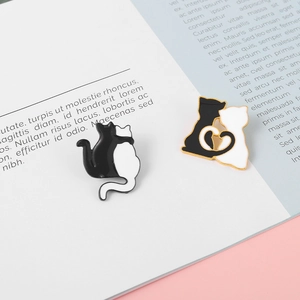 Detail of cat enamel pins with black and white kitten designs on magazine background