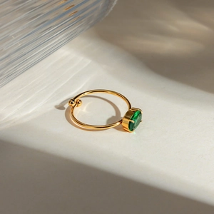 Detailed shot of an 18k gold plated adjustable ring with a green oval zircon stone