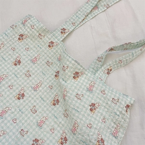 Detail of light green checkered canvas tote featuring cute animal prints and textured fabric