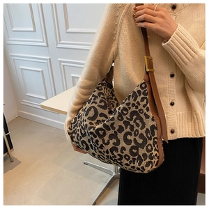Detail of leopard print canvas bag with brown leather strap and metal hardware