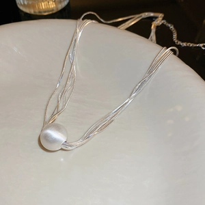 Elegant multi-layered silver choker necklace with a large white pearl pendant on a tray