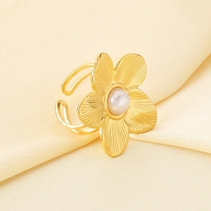 Detailaufnahme eines goldfarbenen Perlenblumenrings auf feiner gelber Seide