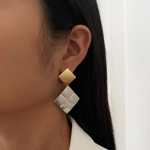 Stylish two-tone geometric drop earrings with gold and silver diamond shapes on model