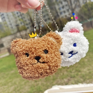 Close-up of cute plush bear and rabbit head keychains with metal bead chains in hand