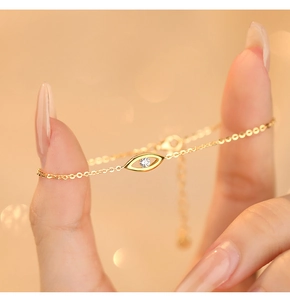 Detail of gold evil eye bracelet on wrist with sparkling zircon and cross chain