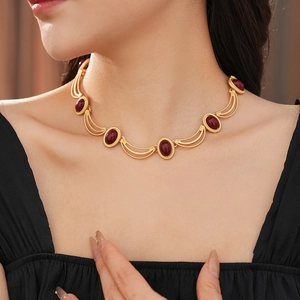 Detail of vintage gold necklace featuring oval red gemstones on a model neck