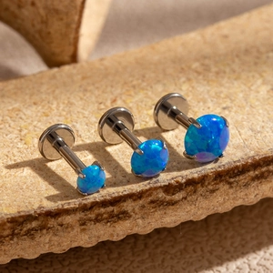 Macro detail of three blue opal flat back studs in varying sizes on stone surface
