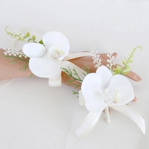 Wedding boutonniere and wrist corsage set with white orchids and greenery on white background