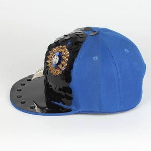 Detail of owl pattern punk cap with black sequins and blue gemstone on flat brim hat