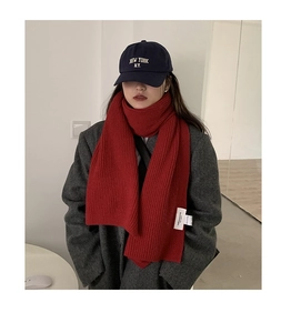 Close-up of red chunky knit scarf paired with a blue baseball cap and grey coat