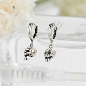 Detail of silver skull earrings with vintage finish and intricate bone texture carvings