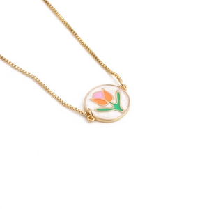 Macro view of golden tulip necklace with colorful enamel inlay on white mother of pearl