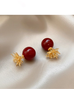 Macro detail of red pearl earrings with intricate gold coral-like cluster accents