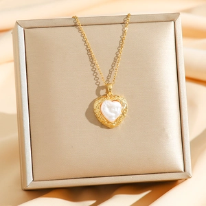 Detailed view of heart-shaped pearl pendant with gold scalloped edge and fine chain