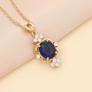 Elegant gold necklace with oval dark blue gemstone surrounded by sparkling crystals